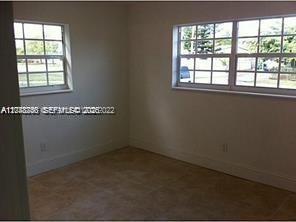 An empty room with beige tile flooring and two windows overlooking a residential street — 1231 NW 190th St, Miami Gardens FL 33169, MIAMI GARDENS, FL