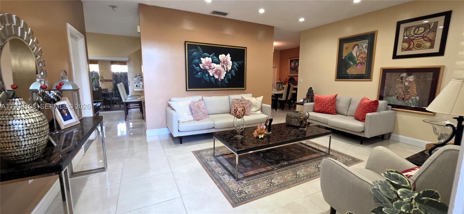 A living room features light-colored sofas, a dark coffee table, and framed wall art — 5769 NW 99th Ave, Doral FL 33178, DORAL, FL