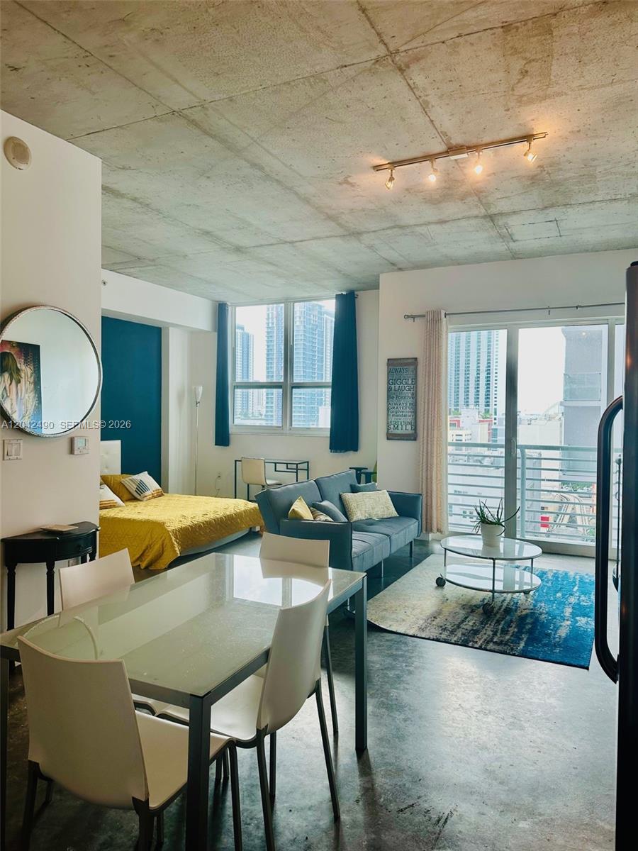 A modern studio apartment features a concrete ceiling, a living area, and a bedroom space — 133 NE 2 AV # 1503, Miami FL 33132, MIAMI, FL