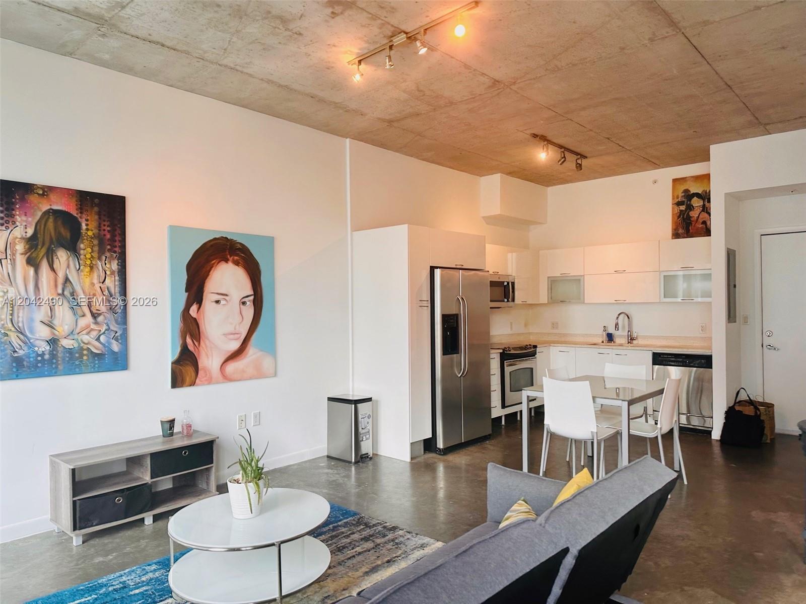 This open-concept living area features a kitchen, dining space, and concrete ceilings and floors — 133 NE 2 AV # 1503, Miami FL 33132, MIAMI, FL