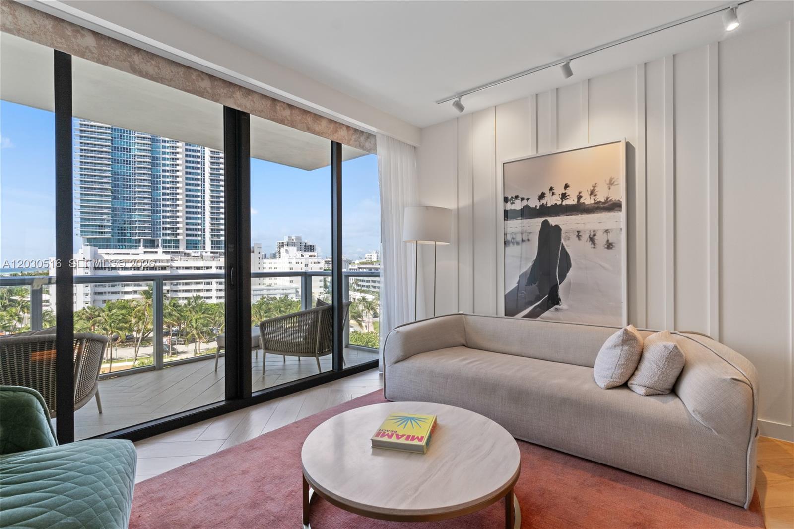 A modern living room features a beige sofa, round coffee table, and balcony with city views — 2201 Collins Ave # 707, Miami Beach FL 33139, MIAMI BEACH, FL