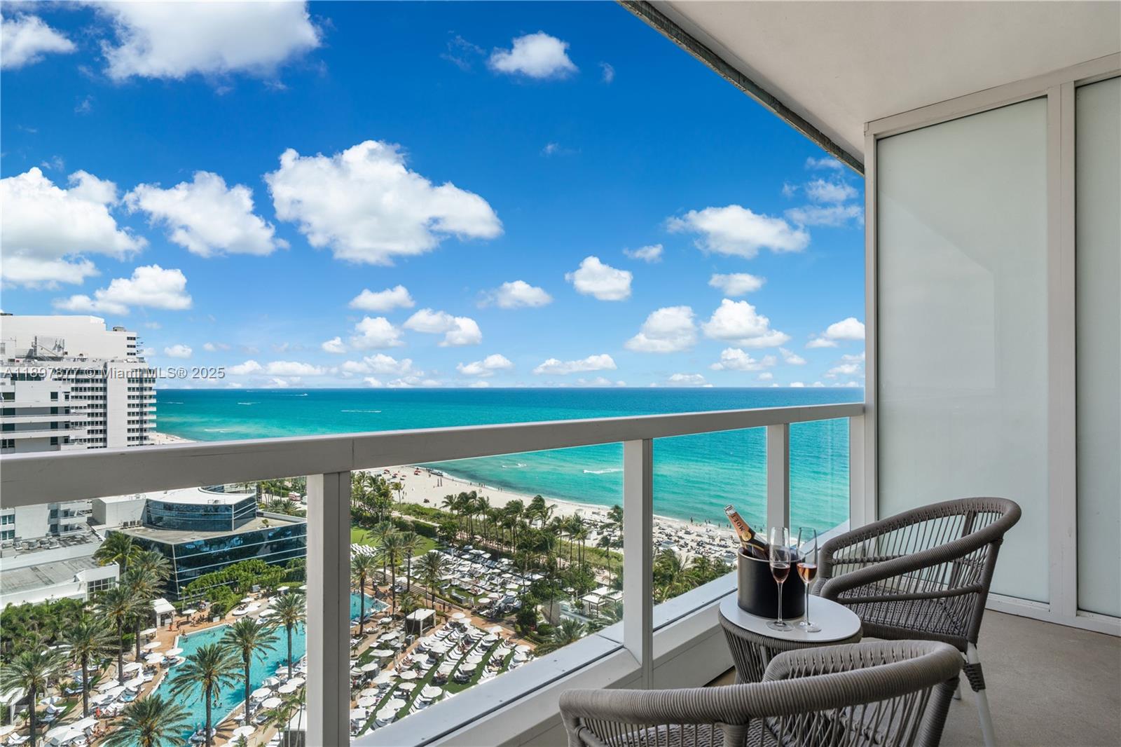 A balcony overlooks a beach and ocean with two chairs and a champagne bucket — 4391 Collins Ave # 1403, Miami Beach FL 33140, MIAMI BEACH, FL