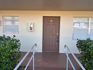 A brown front door is centered between two windows and metal handrails on a porch — 7300 NW 4th Place # 105, Margate FL 33063, MARGATE, FL