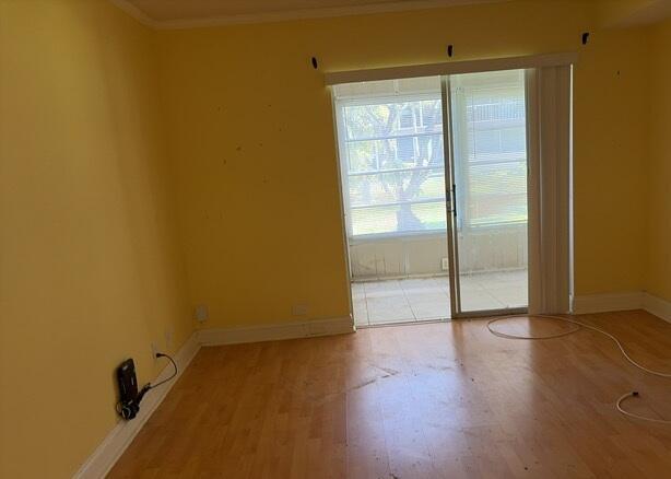 An empty room with yellow walls, light wood flooring, and a sliding glass door — 7300 NW 4th Place # 105, Margate FL 33063, MARGATE, FL