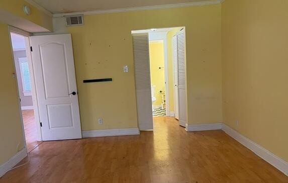 A room with yellow walls, light wood flooring, a white door, and a bathroom entrance — 7300 NW 4th Place # 105, Margate FL 33063, MARGATE, FL
