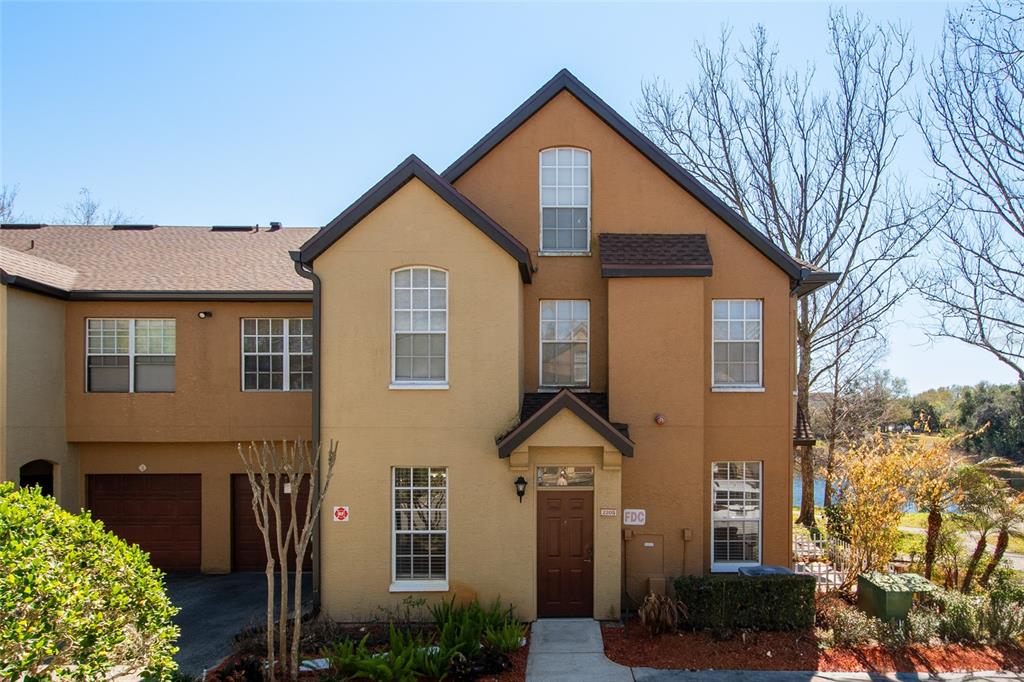 A three-story tan stucco townhouse with a brown front door and an attached garage — 6384 RALEIGH STREET UNIT 2205, ORLANDO, FL