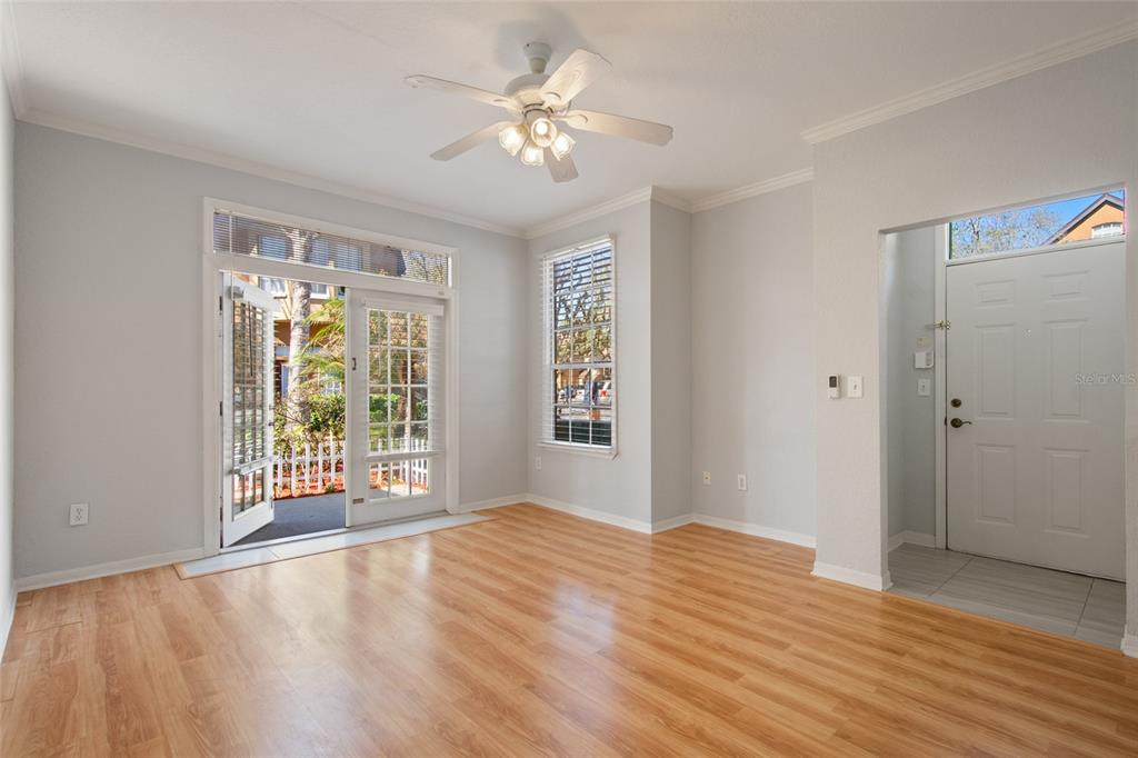 An empty living room with light wood floors, a ceiling fan, and glass patio doors — 6384 RALEIGH STREET UNIT 2205, ORLANDO, FL