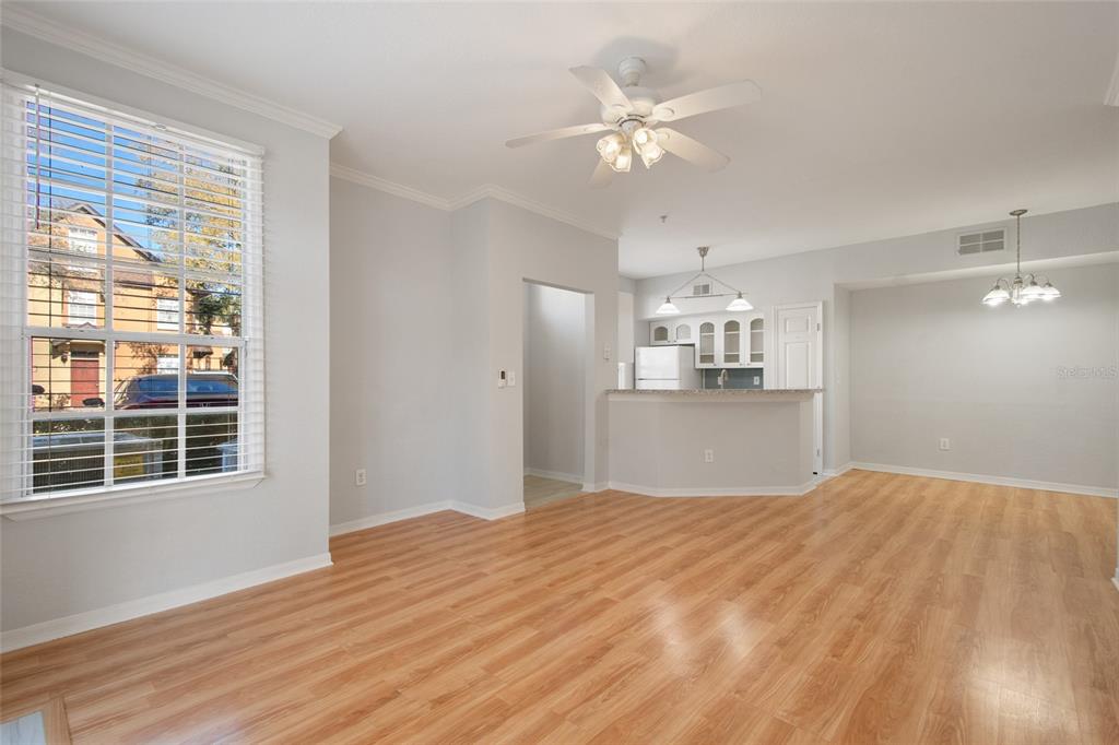 A living room with light wood flooring, a ceiling fan, and an open kitchen area — 6384 RALEIGH STREET UNIT 2205, ORLANDO, FL