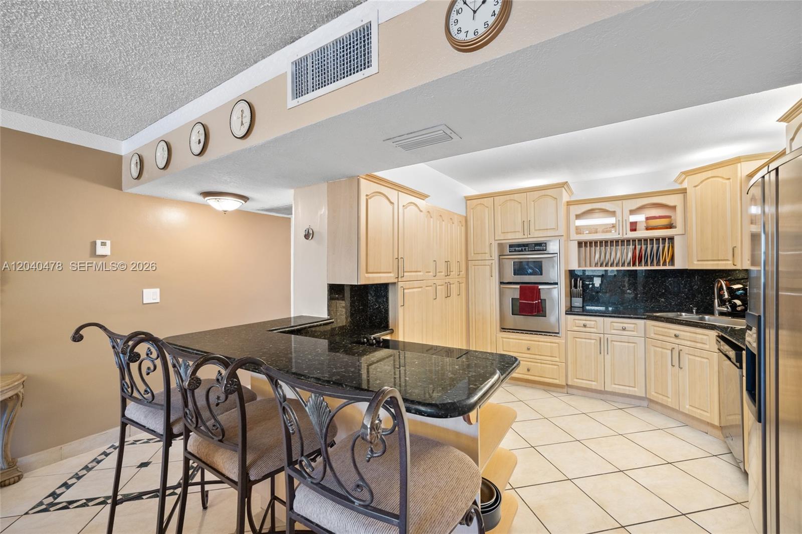 A kitchen features light wood cabinets, black granite countertops, and a breakfast bar with stools — 3725 S Ocean Dr # 1124, Hollywood FL 33019, HOLLYWOOD, FL