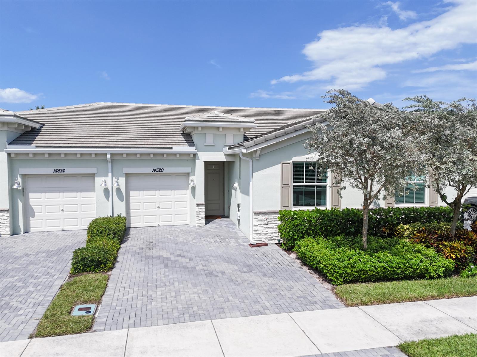 A light-colored duplex with two garage doors, a paved driveway, and landscaped front yard — 14520 Wiley Range Road, Delray Beach FL 33446, DELRAY BEACH, FL