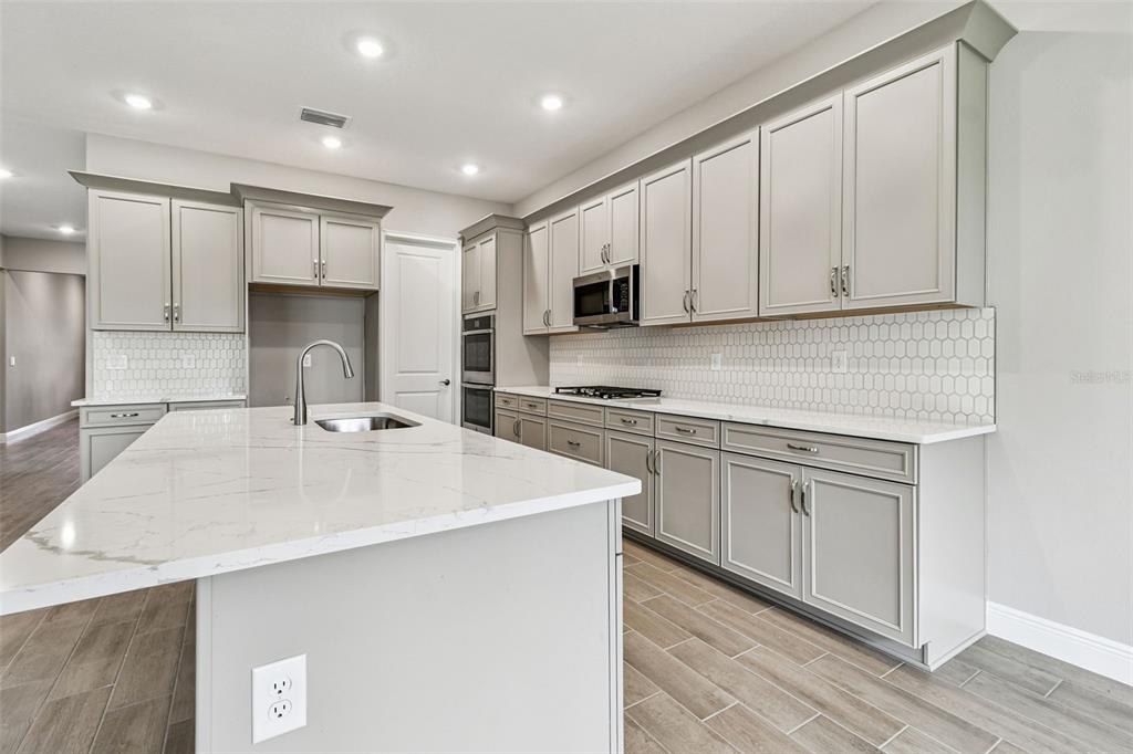 A modern kitchen features light gray cabinets, white marble countertops, and a large center island — 12309 WHITE BLOSSOM COURT, PARRISH, FL