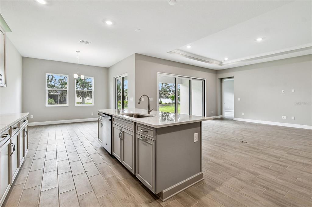 A kitchen with a gray island, quartz countertops, and light wood-look tile flooring — 12309 WHITE BLOSSOM COURT, PARRISH, FL