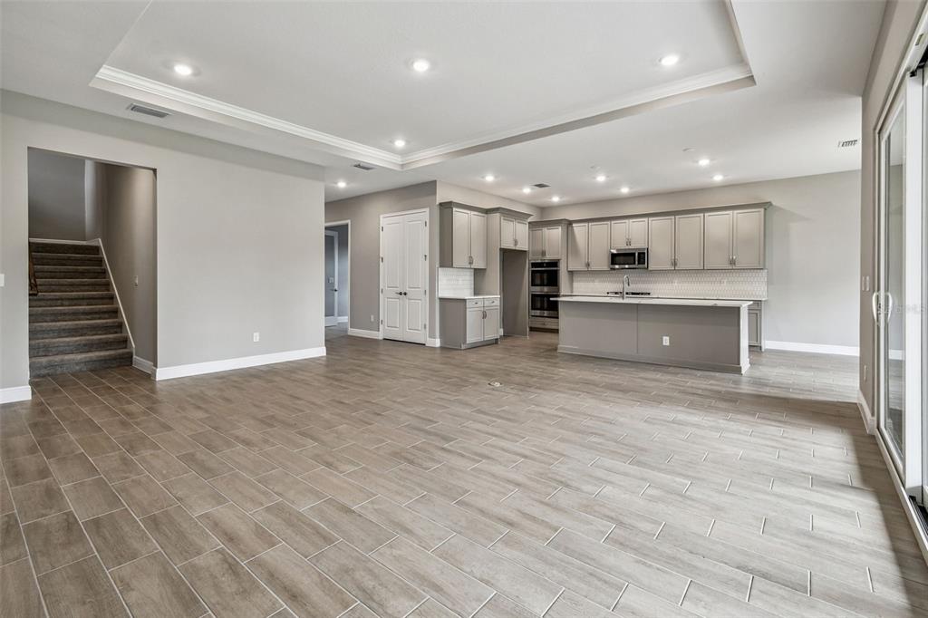 An open-concept kitchen and living area featuring light gray cabinetry, tile flooring, and recessed lighting — 12309 WHITE BLOSSOM COURT, PARRISH, FL