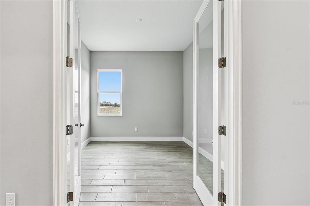 A room with gray walls, wood-look tile flooring, and glass-paneled French doors — 12309 WHITE BLOSSOM COURT, PARRISH, FL