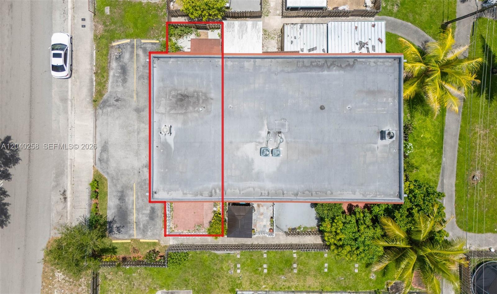 An aerial view shows a flat-roofed building with a red-outlined section and adjacent parking — 1450 NE 151st St # 101, Miami FL 33162, MIAMI, FL