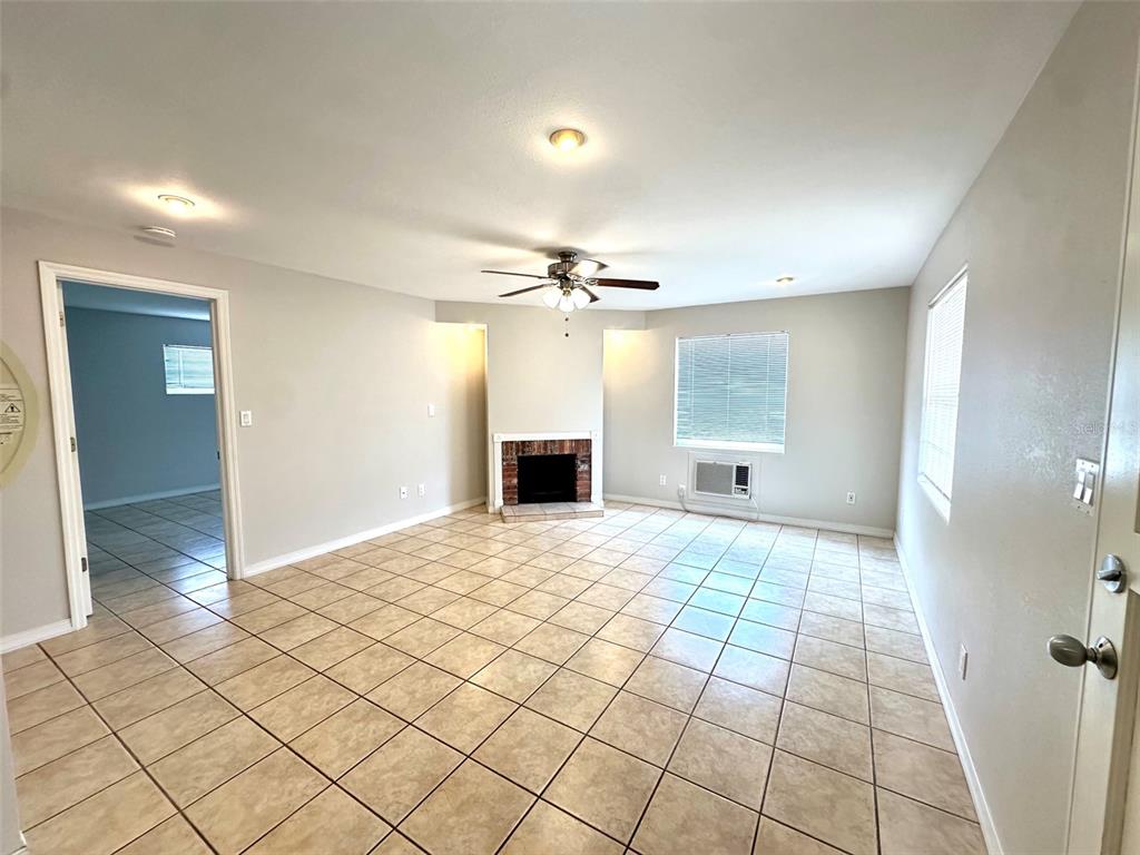 A living room features beige tile flooring, a brick fireplace, and a ceiling fan — 1458 CLEVELAND STREET, CLEARWATER, FL