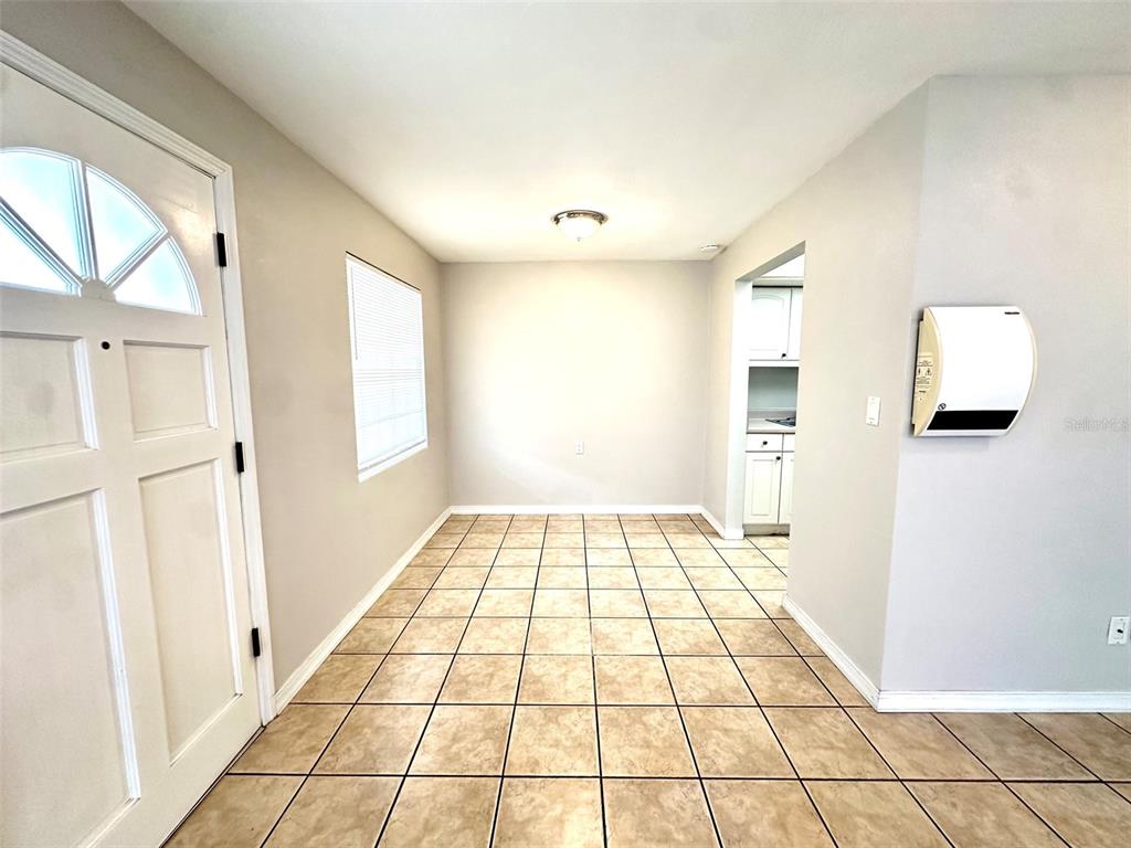 A room with light-colored walls, tiled flooring, a front door, and a wall-mounted heater — 1458 CLEVELAND STREET, CLEARWATER, FL