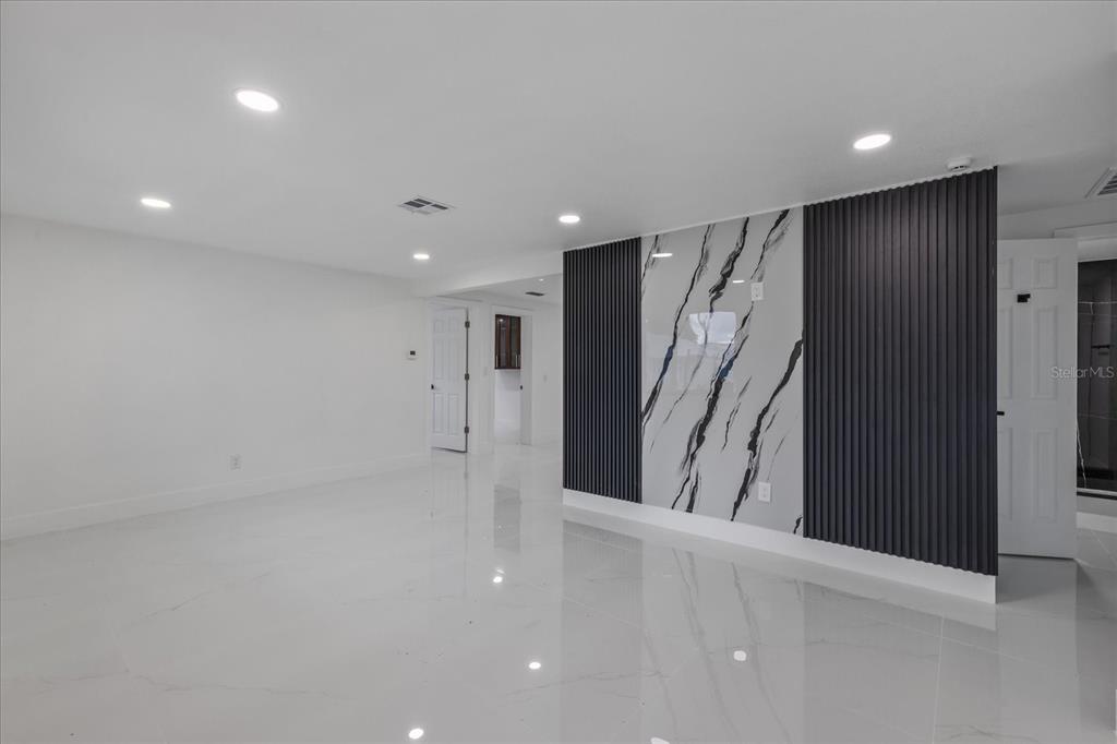 A room with white tile floors, recessed lighting, and a black-and-white marble accent wall — 4853 ROSEDALE LANE, HOLIDAY, FL