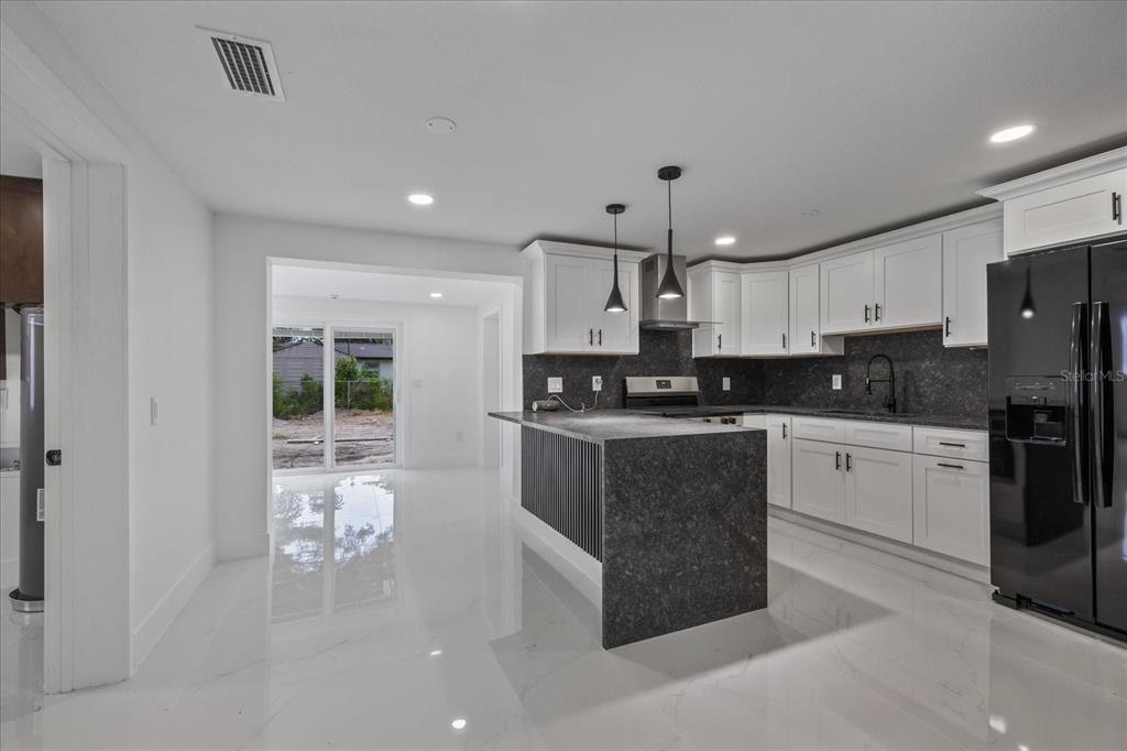 A kitchen with white cabinets, a dark stone island, and glossy white tile flooring — 4853 ROSEDALE LANE, HOLIDAY, FL