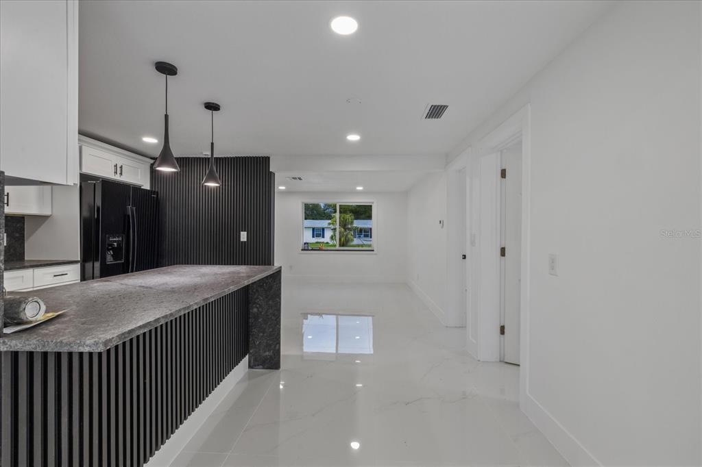A modern kitchen features a dark slatted island, white cabinetry, and glossy white tile flooring — 4853 ROSEDALE LANE, HOLIDAY, FL