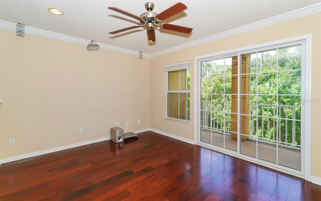 An empty room features hardwood floors, a ceiling fan, and sliding glass doors to a balcony — 7339 BLACK WALNUT WAY, LAKEWOOD RANCH, FL