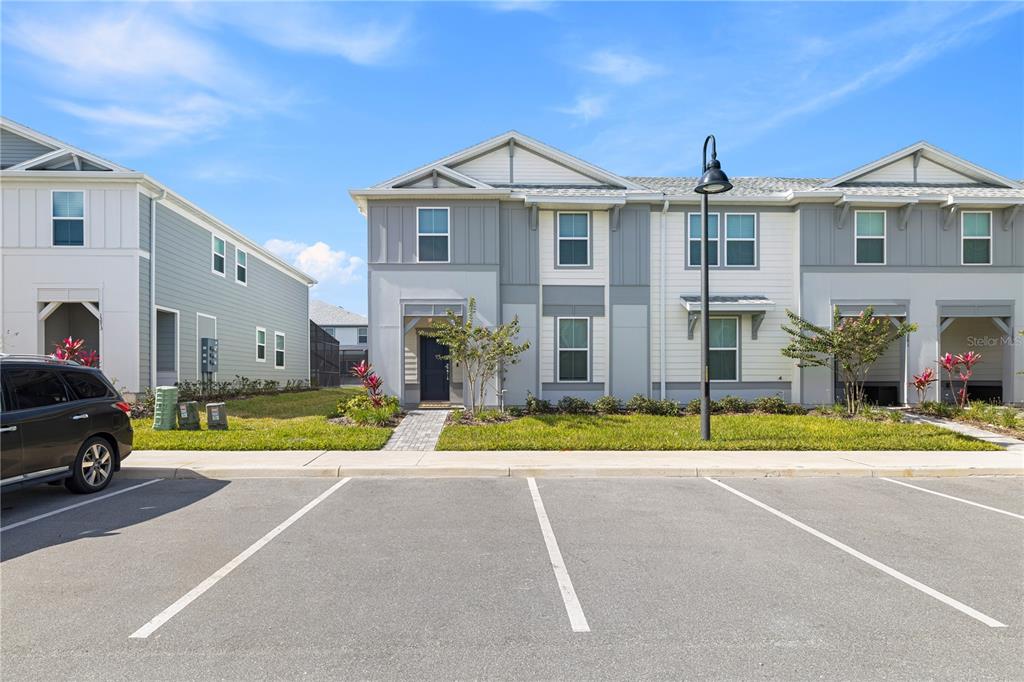 A two-story townhome exterior features gray and white siding with a paved walkway — 1277 BLUE ISLAND DRIVE, CLERMONT, FL