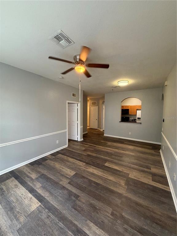 An open living area features gray walls, wood-look flooring, a ceiling fan, and an arched pass-through — 6100 STEVENSON DRIVE UNIT 207, ORLANDO, FL