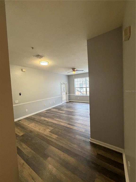 An empty living area features wood-look flooring, light gray walls, and a ceiling fan — 6100 STEVENSON DRIVE UNIT 207, ORLANDO, FL