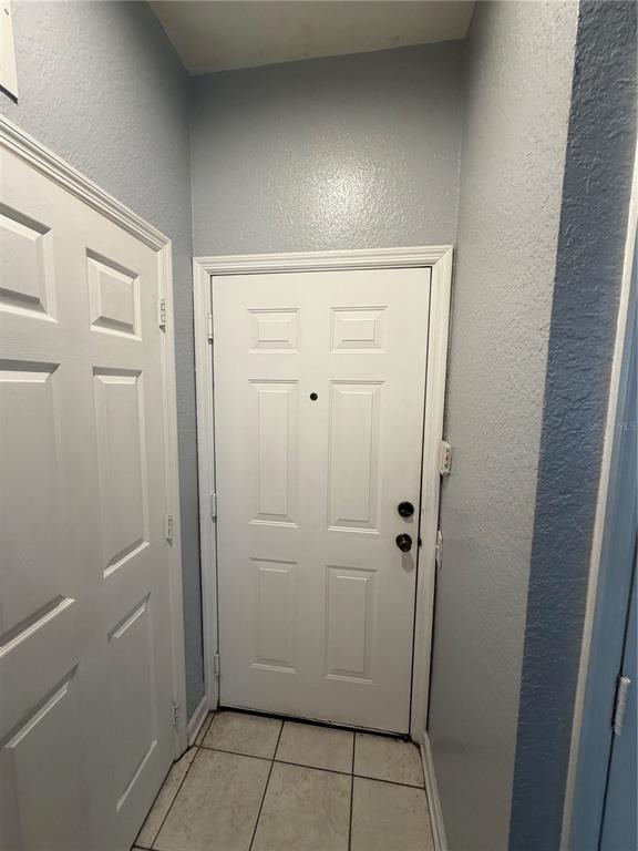 An interior entryway features a white front door, a side door, and tiled flooring — 6100 STEVENSON DRIVE UNIT 207, ORLANDO, FL