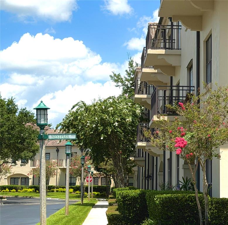 A multi-story apartment building with balconies stands beside a sidewalk and a street sign — 909 WATERSIDE LANE UNIT 205, CELEBRATION, FL
