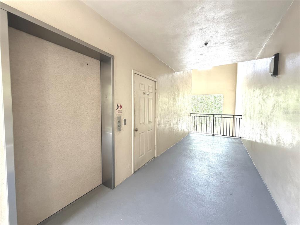 An elevator door and a white door are located in a hallway with gray flooring — 909 WATERSIDE LANE UNIT 205, CELEBRATION, FL