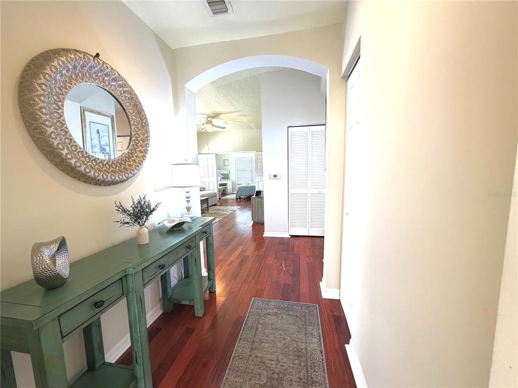 A hallway with hardwood floors leads to an arched entryway into a living area — 909 WATERSIDE LANE UNIT 205, CELEBRATION, FL