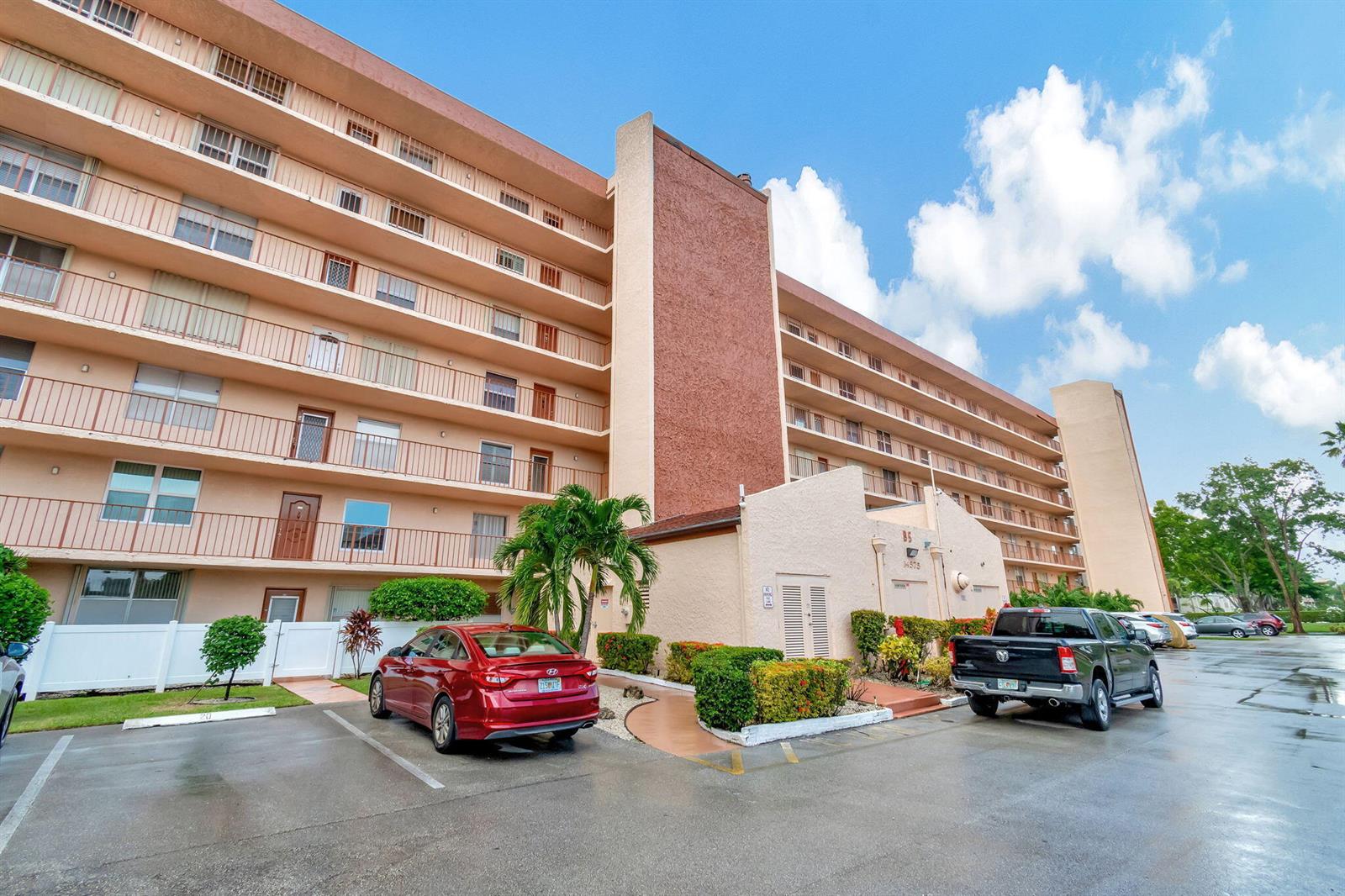 A multi-story apartment building with balconies, a parking lot, and two parked vehicles — 14575 Bonaire Boulevard # 402, Delray Beach FL 33446, DELRAY BEACH, FL
