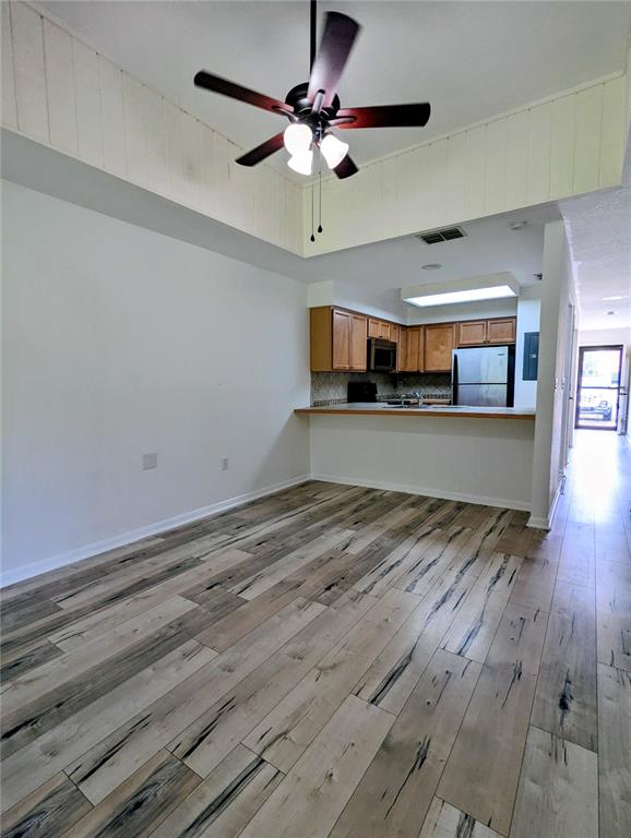 This room features wood-look flooring, a vaulted ceiling with a fan, and an open kitchen — 6125 TOPHER TRAIL UNIT 62A, MULBERRY, FL