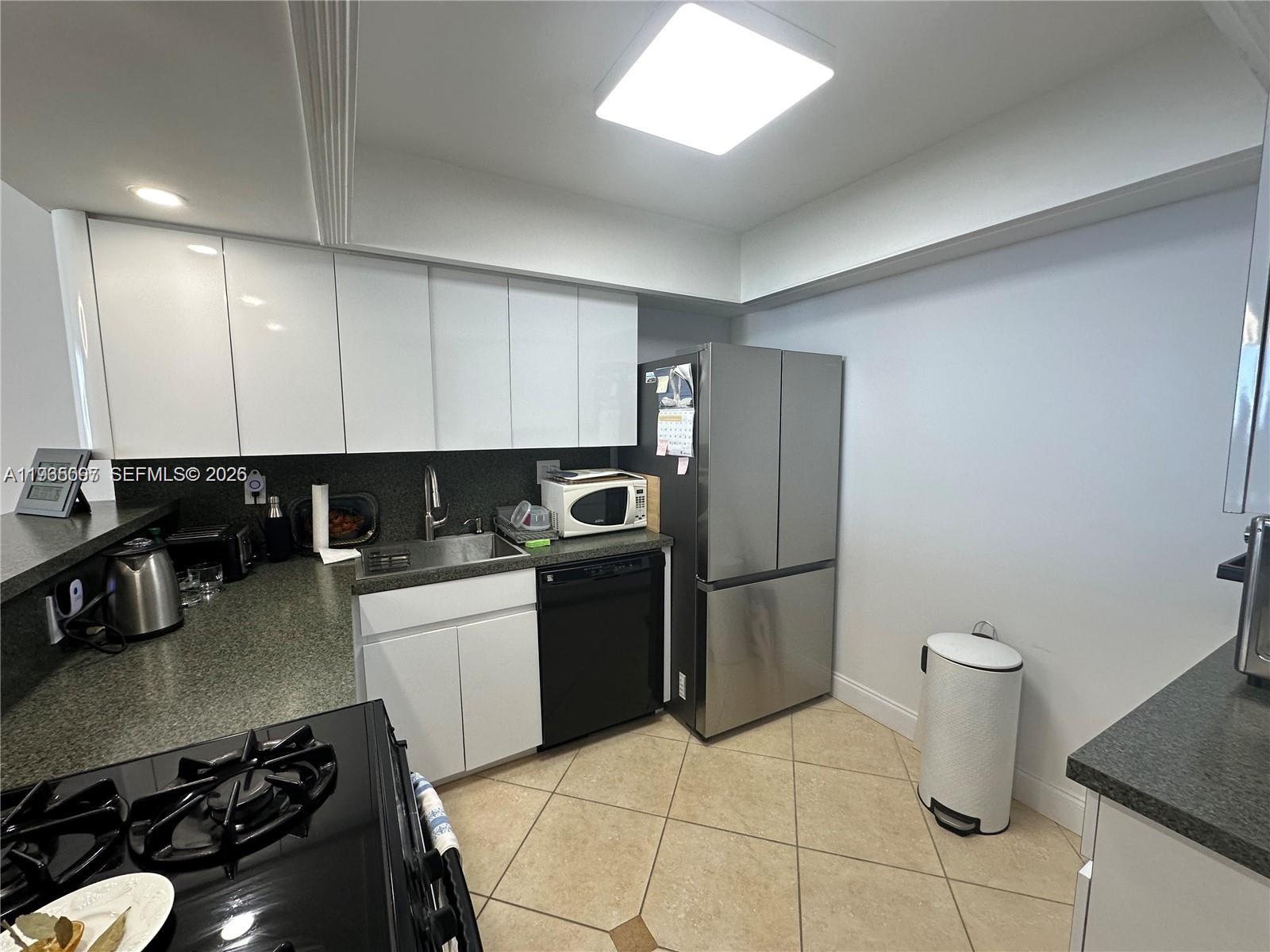 A kitchen features white cabinets, stainless steel appliances, dark countertops, and light tile flooring — 2030 S Ocean Dr # 2217, Hallandale Beach FL 33009, HALLANDALE BEACH, FL
