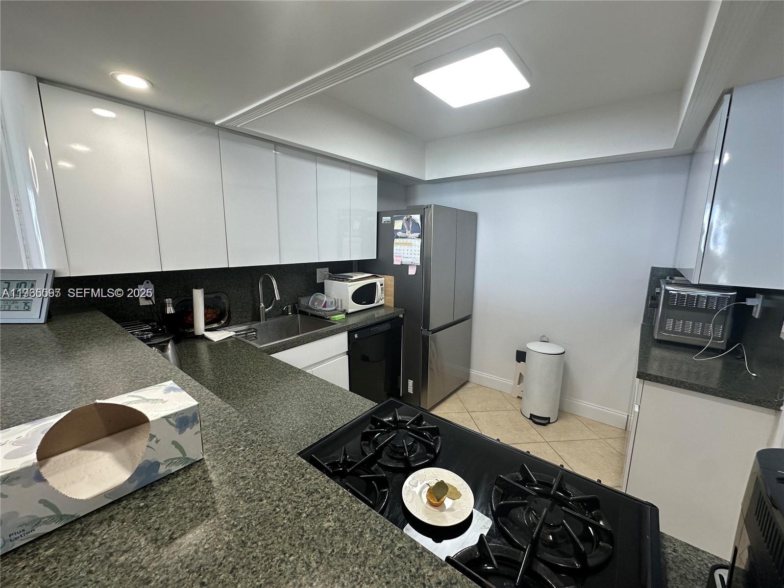 A kitchen features white cabinets, dark granite countertops, a gas cooktop, and stainless steel appliances — 2030 S Ocean Dr # 2217, Hallandale Beach FL 33009, HALLANDALE BEACH, FL