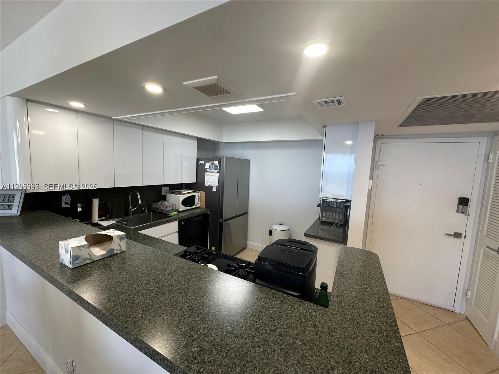 A kitchen features white cabinets, dark granite countertops, stainless steel appliances, and recessed lighting — 2030 S Ocean Dr # 2217, Hallandale Beach FL 33009, HALLANDALE BEACH, FL