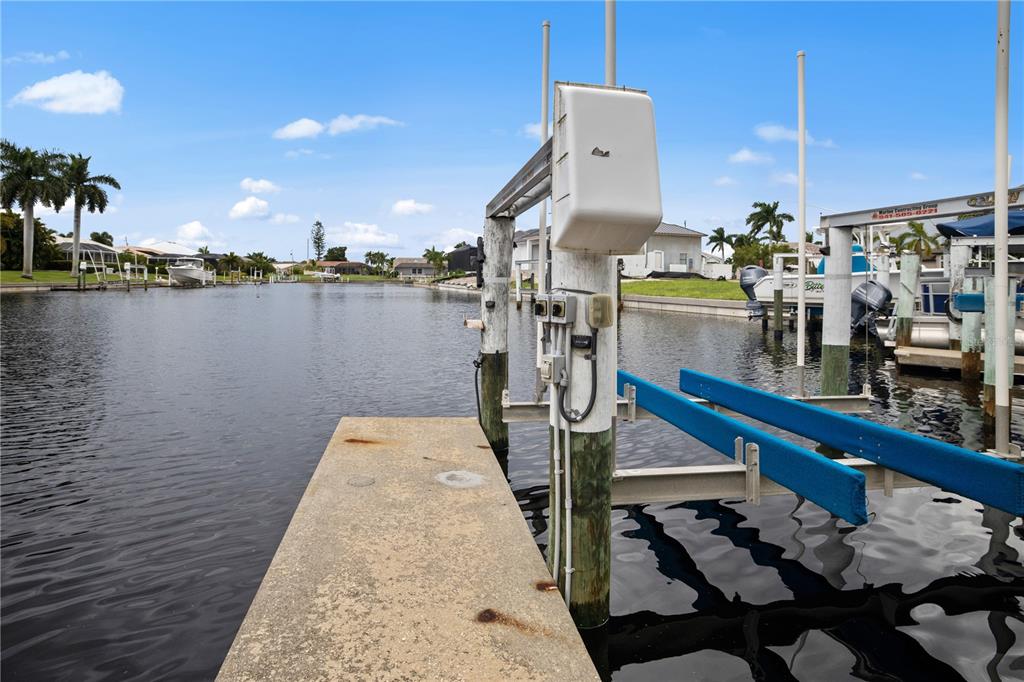 A concrete dock features a boat lift with blue bunks over a residential canal — 1217 GORDA CAY LANE, PUNTA GORDA, FL
