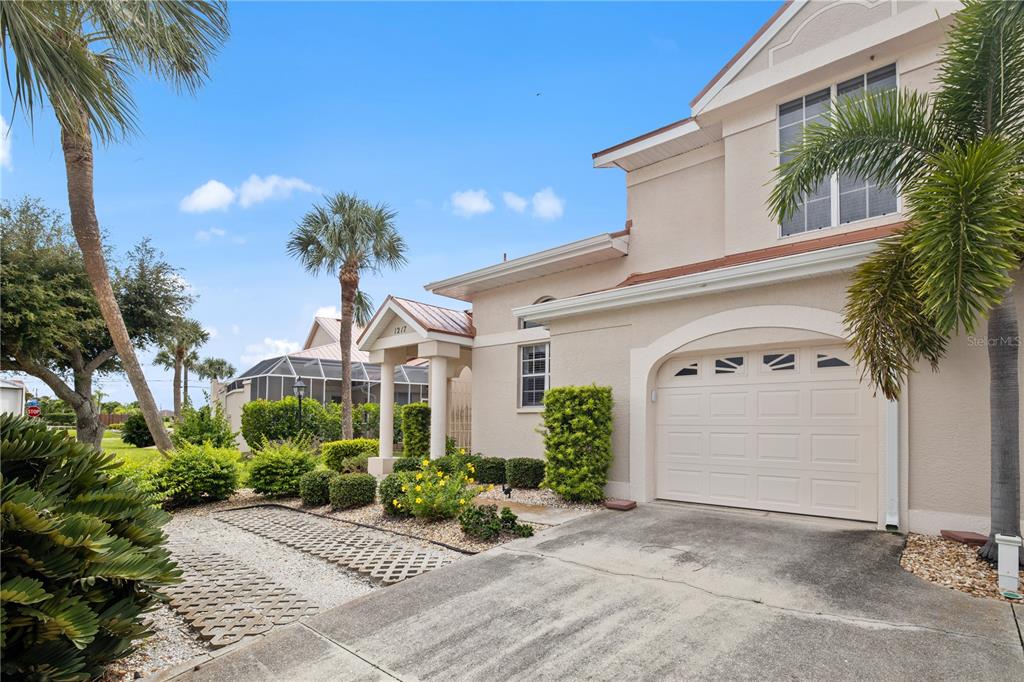 A two-story beige house with a garage, a paved driveway, and palm trees — 1217 GORDA CAY LANE, PUNTA GORDA, FL