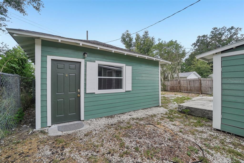A green detached structure with a dark door and white trim sits on gravel — 1533 E ELM ROAD, LAKELAND, FL