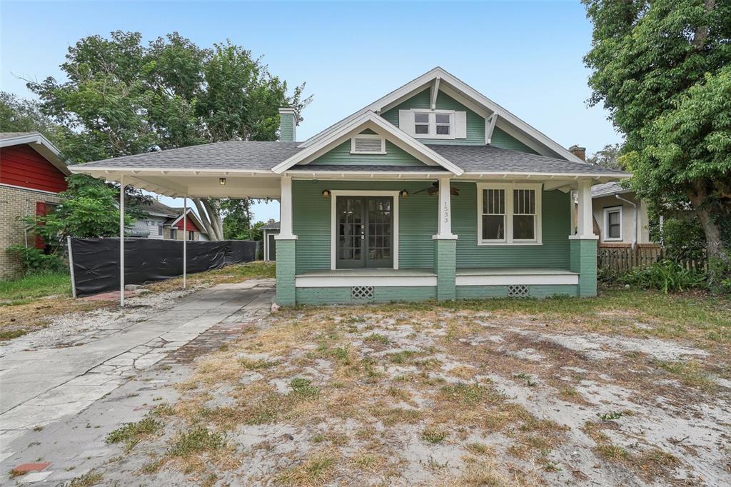 A green bungalow with a front porch, a carport, and a gabled roof — 1533 E ELM ROAD, LAKELAND, FL