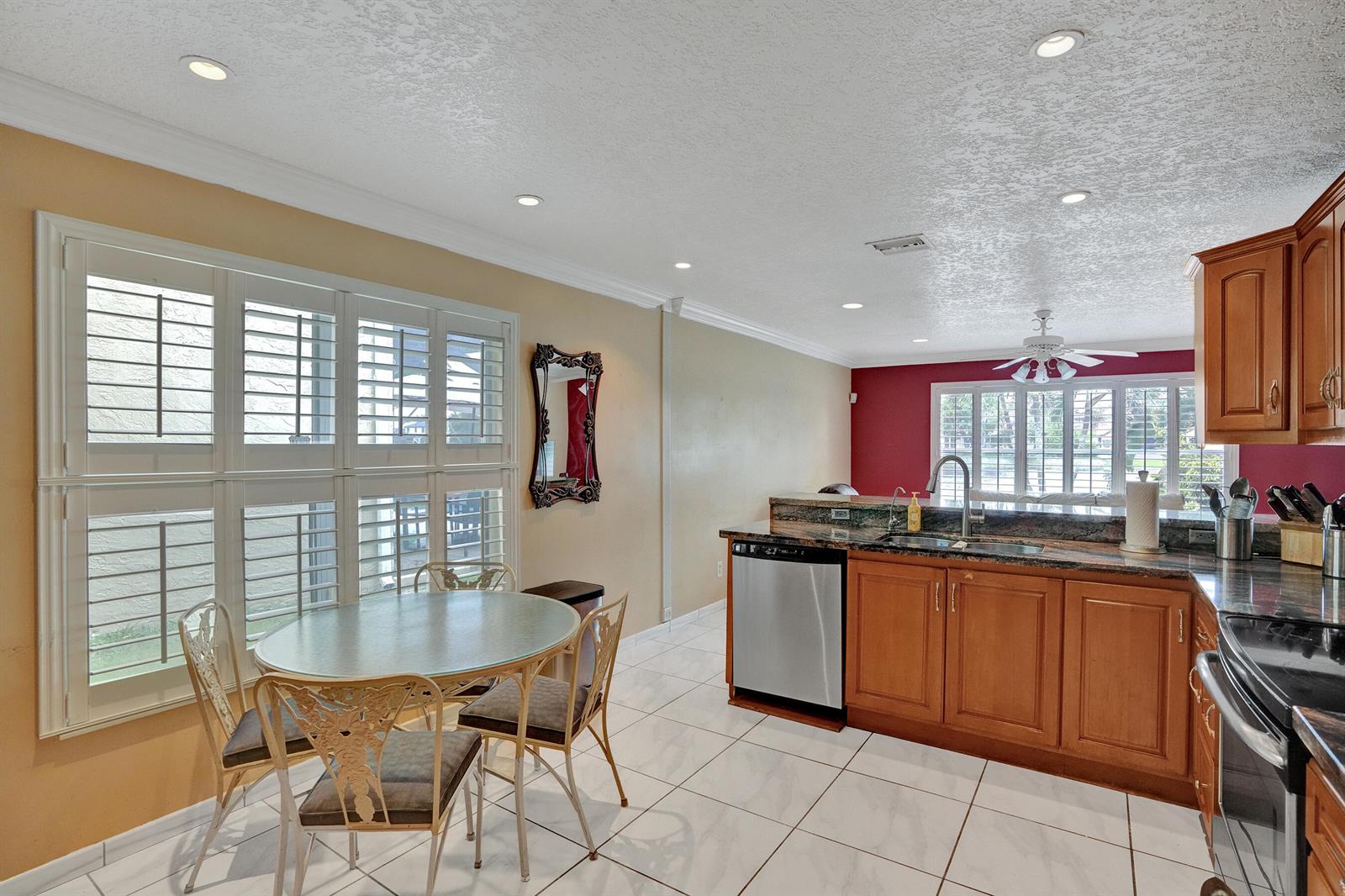 A kitchen with wood cabinets, granite countertops, and a dining area with plantation shutters — 18144 SW 20th Street, Miramar FL 33029, MIRAMAR, FL