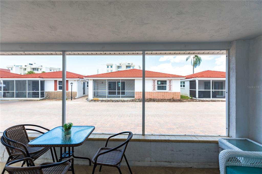 A screened-in porch overlooks a paved courtyard with several small houses featuring red tile roofs — 6154 MIDNIGHT PASS ROAD UNIT D15, SARASOTA, FL