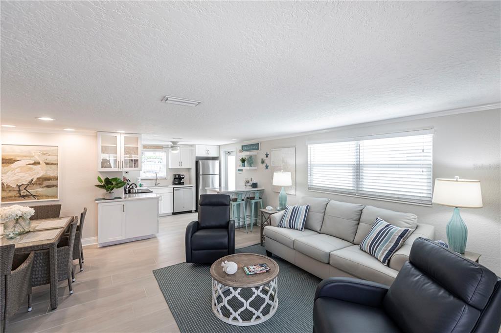 An open-concept living and dining area features light tile floors, white cabinetry, and neutral furniture — 6154 MIDNIGHT PASS ROAD UNIT D15, SARASOTA, FL