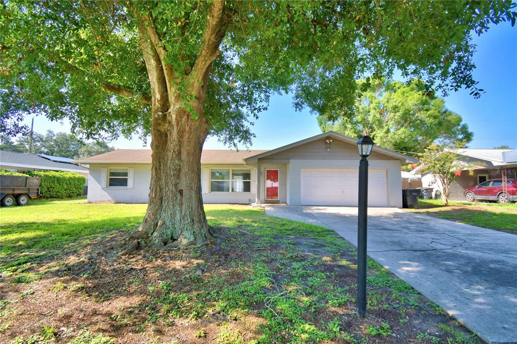 A single-story house with a brick facade, a large front tree, and a concrete driveway — 153 BROWNING CIRCLE, WINTER HAVEN, FL