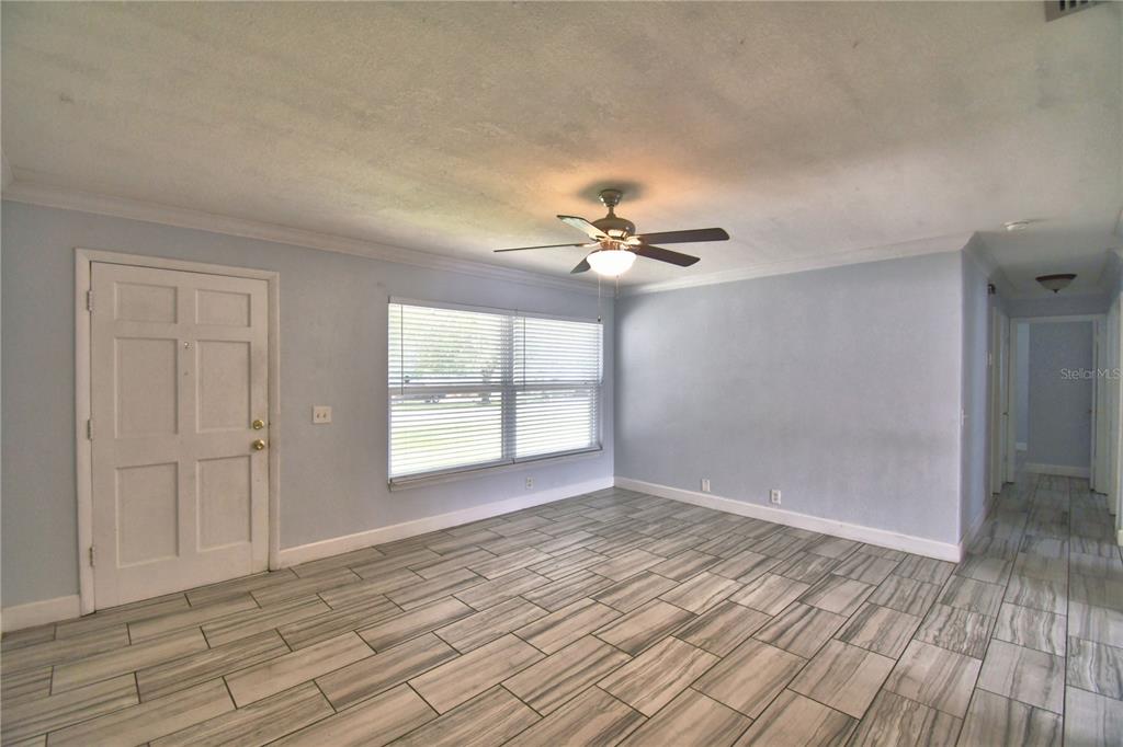 A living room features light blue walls, wood-look tile flooring, and a ceiling fan — 153 BROWNING CIRCLE, WINTER HAVEN, FL