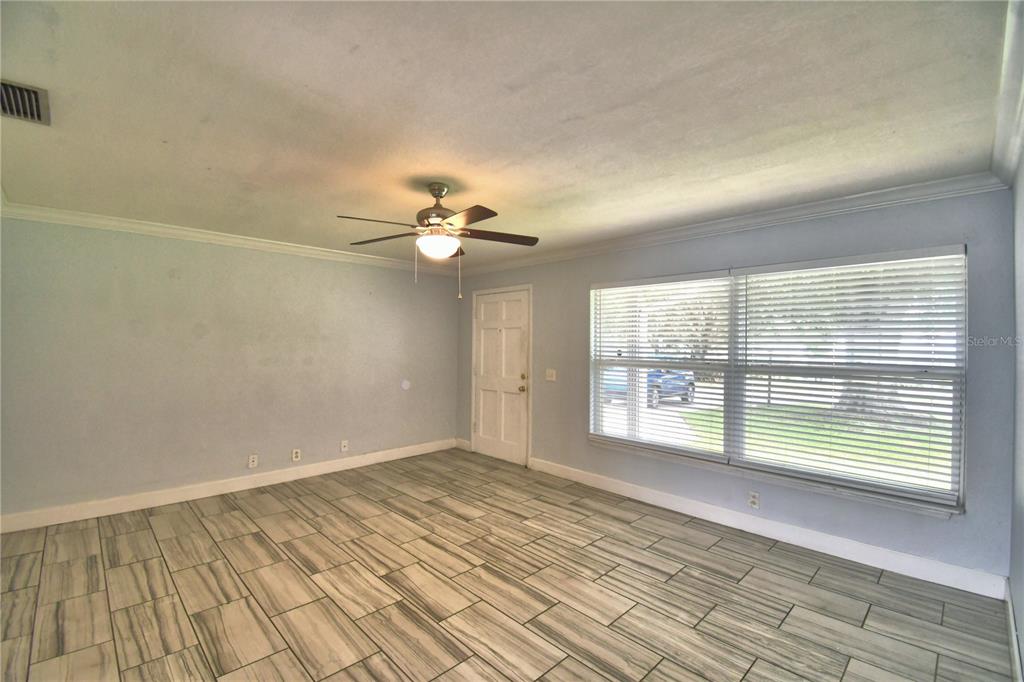 An empty room with light blue walls, wood-look tile flooring, and a ceiling fan — 153 BROWNING CIRCLE, WINTER HAVEN, FL