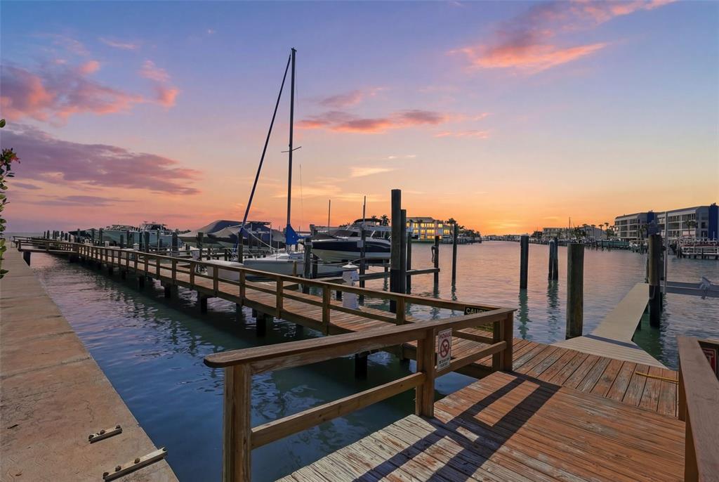 A wooden pier extends into a marina with docked boats under a sunset sky — 128 1ST STREET E. UNIT 102, TIERRA VERDE, FL
