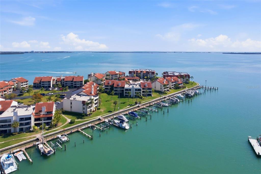 An aerial view shows waterfront condominium buildings with a long boat dock and marina — 128 1ST STREET E. UNIT 102, TIERRA VERDE, FL