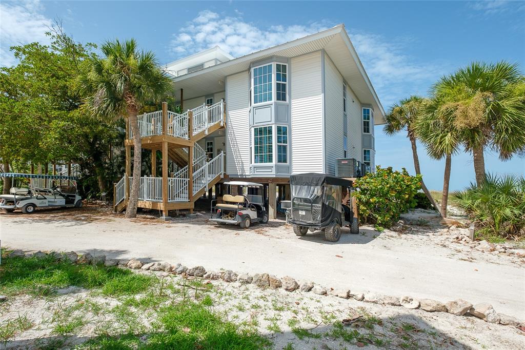 A two-story house on stilts with an exterior staircase, golf carts, and palm trees — 7462 PALM ISLAND DRIVE UNIT 3113, PLACIDA, FL